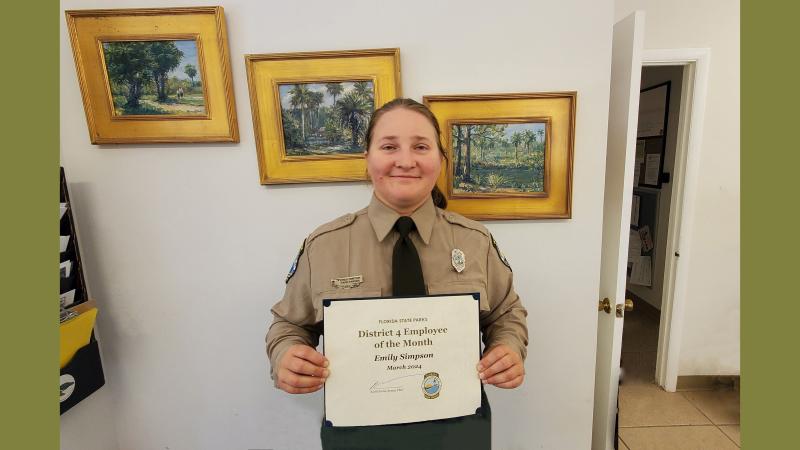 Park Ranger in uniform holding an award certificate.