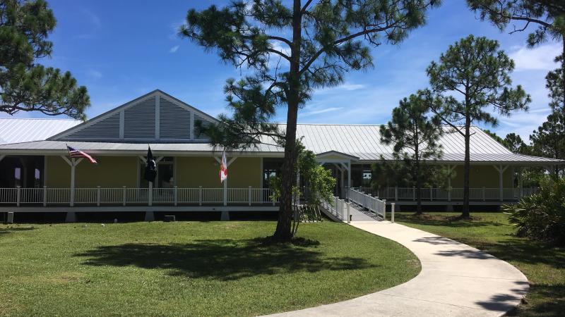 A yellow and white building surrounded by slash pine trees.