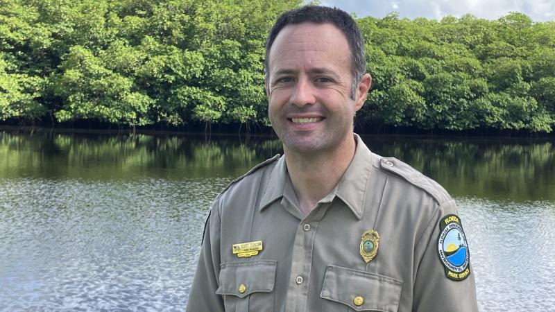 Image of smiling park manager standing in front of a river